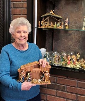 charlotte leeth holding one of her nativity scenes in front of the display