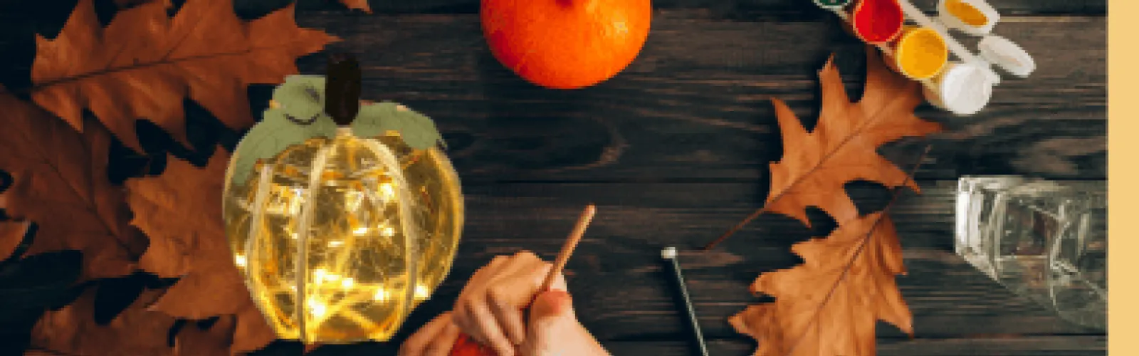 Leaves, paint, and a glowing pumpkin on a table. 