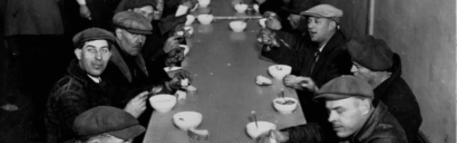 A 1930s photo of men sitting at a table and eating. 