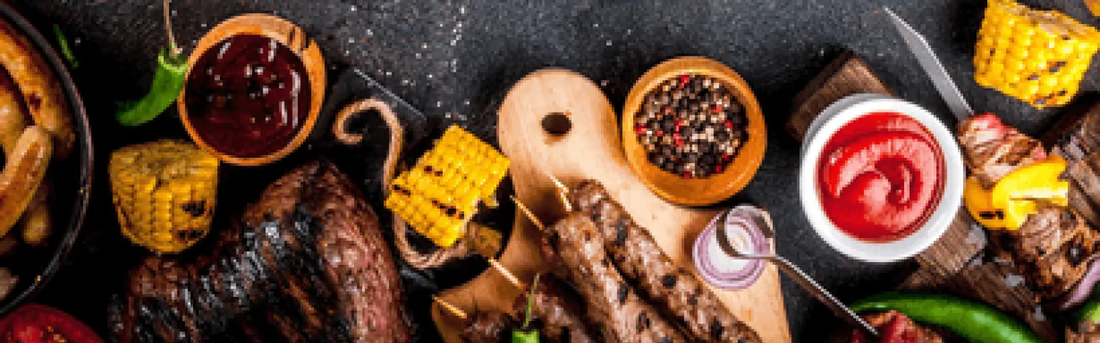 Various BBQ dishes and pieces of corn on the cob. 