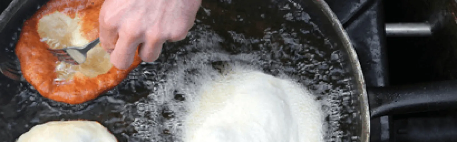 Hands making food in a boiling pot. 